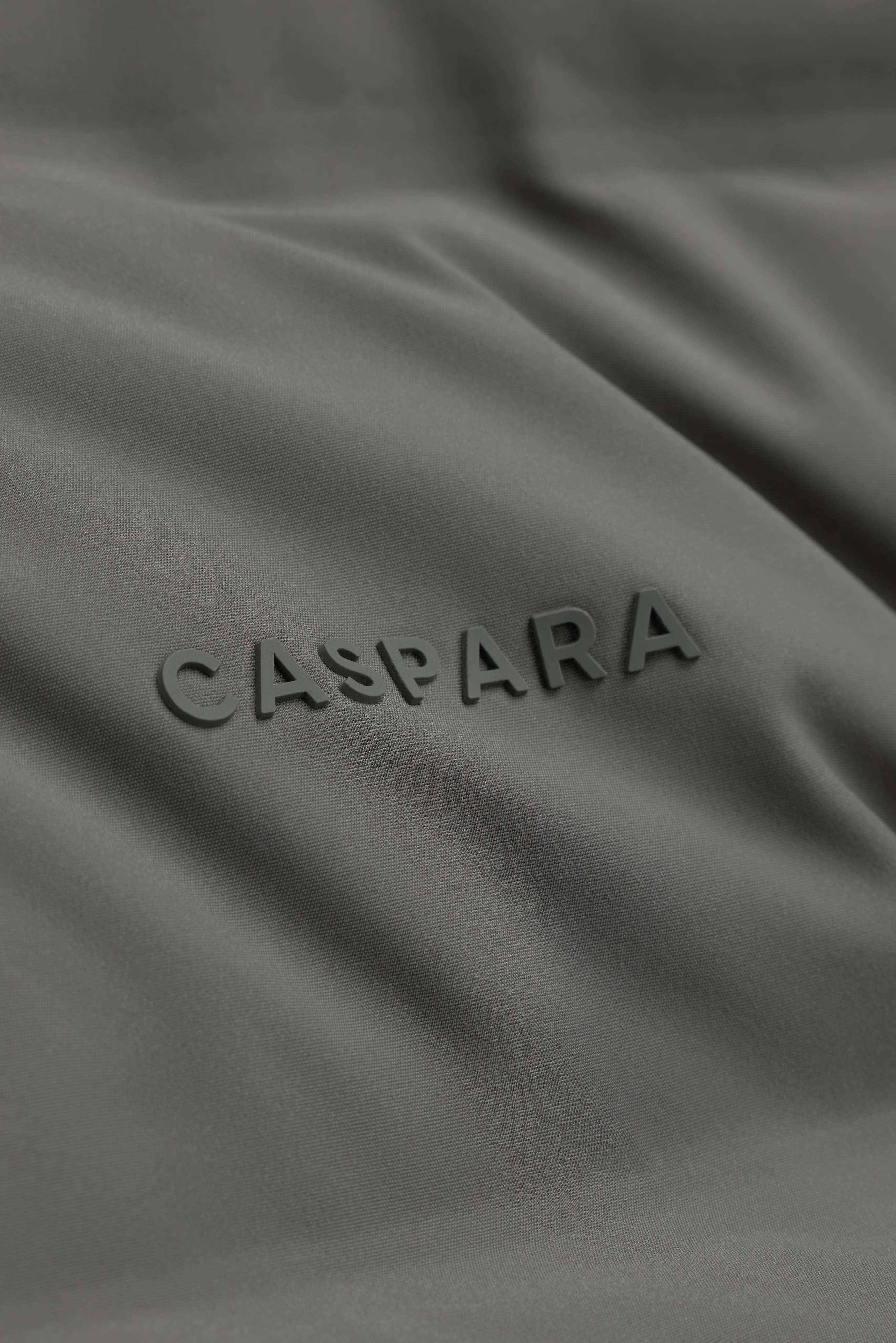 Close-up of the raised CASPARA logo on the khaki Aurora Puffer Jacket.